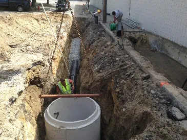 Mounds of excavated soil and gravel are scattered around the site. These materials will be used for backfilling, grading, and roadbed preparation.