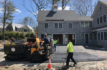 Paving crew using a track asphalt paver machine to install a large residential driveway in Chestnut Hill, MA