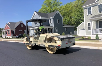 Heavy Ingersoll Rand double-drum roller compacting fresh asphalt on a residential street in Devens, MA