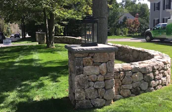 Natural stone entrance column with lantern beside a bluestone walkway in Wellesley, Massachusetts