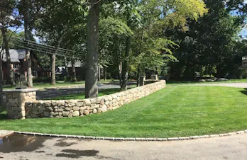 Curved natural stone retaining wall and landscape masonry in Wellesley, Massachusetts