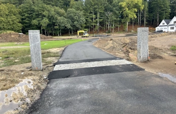 Decorative stone driveway entrance with masonry columns in Concord, Massachusetts
