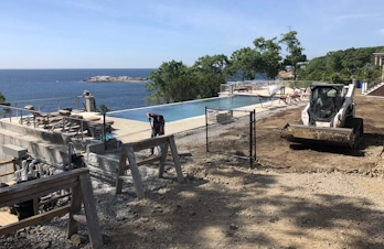 Graded backyard with infinity pool and retaining walls in Gloucester, Massachusetts