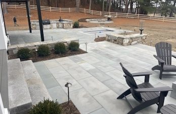 Lap pool with outdoor kitchen, fire pit, and natural stone patio in Concord, Massachusetts