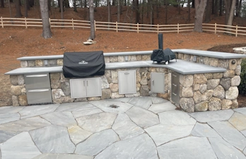 Outdoor kitchen with built-in pizza oven and natural stone patio in Concord, Massachusetts