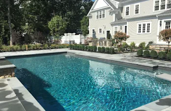 Outdoor kitchen overlooking a swimming pool with bluestone patio in Wellesley, Massachusetts