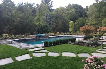 Custom bluestone pool patio and spa with natural stone hardscaping in Wellesley, Massachusetts