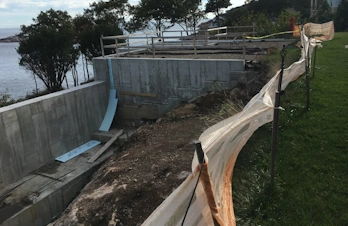 Natural stone retaining wall supporting an infinity pool in Gloucester, Massachusetts