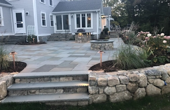 Raised paver patio with outdoor kitchen and fire pit in Concord, Massachusetts
