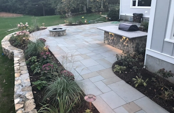 Elevated outdoor living space with fire pit and natural stone patio in Concord, Massachusetts
