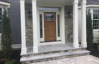 Front porch with natural stone veneer walls and masonry steps in Groton, Massachusetts