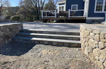 Wide natural stone steps leading to a backyard patio in Holliston, Massachusetts