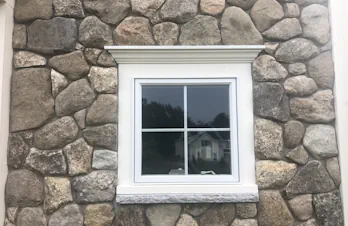 Stone veneer exterior surrounding a residential window in Groton, Massachusetts